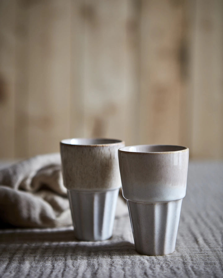 Cala kopperne i beige/multifarvet i sin let koniske form på spisebord med dug