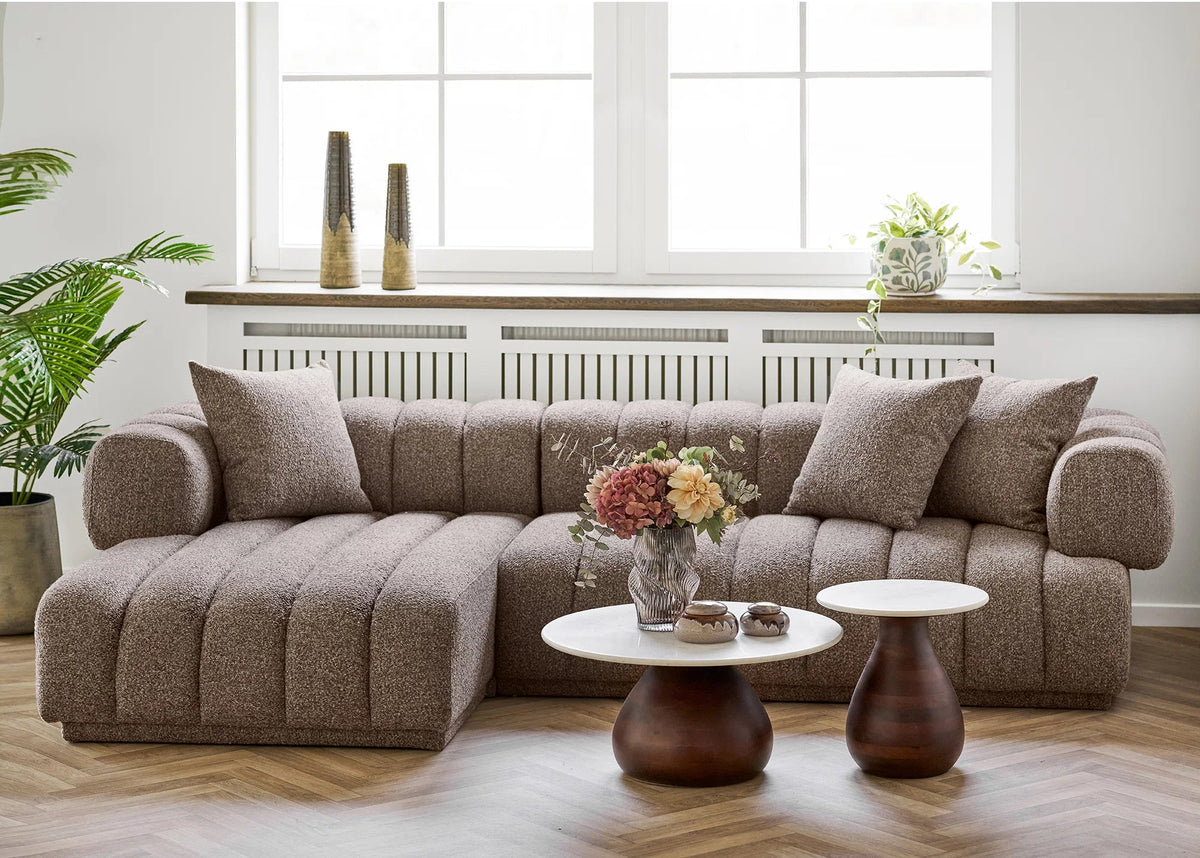 Aurora sofa i brun med venstrevendt chaiselong og tre puder i en lys stue med runde sofaborde.