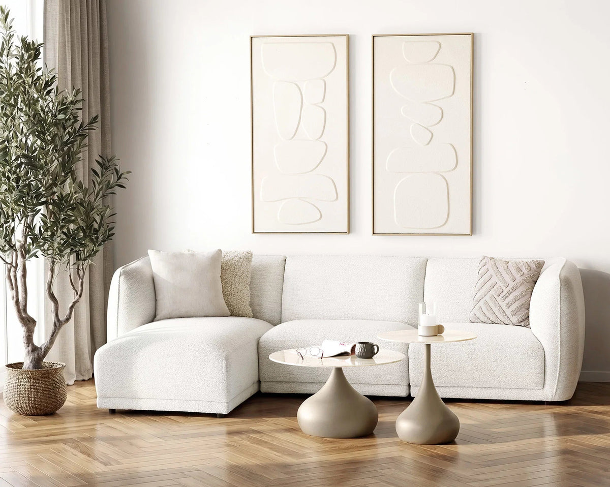 Noor sofa i off-white med venstrevendt chaiselong i en lys stue med runde sofaborde og et stort grønt træ.