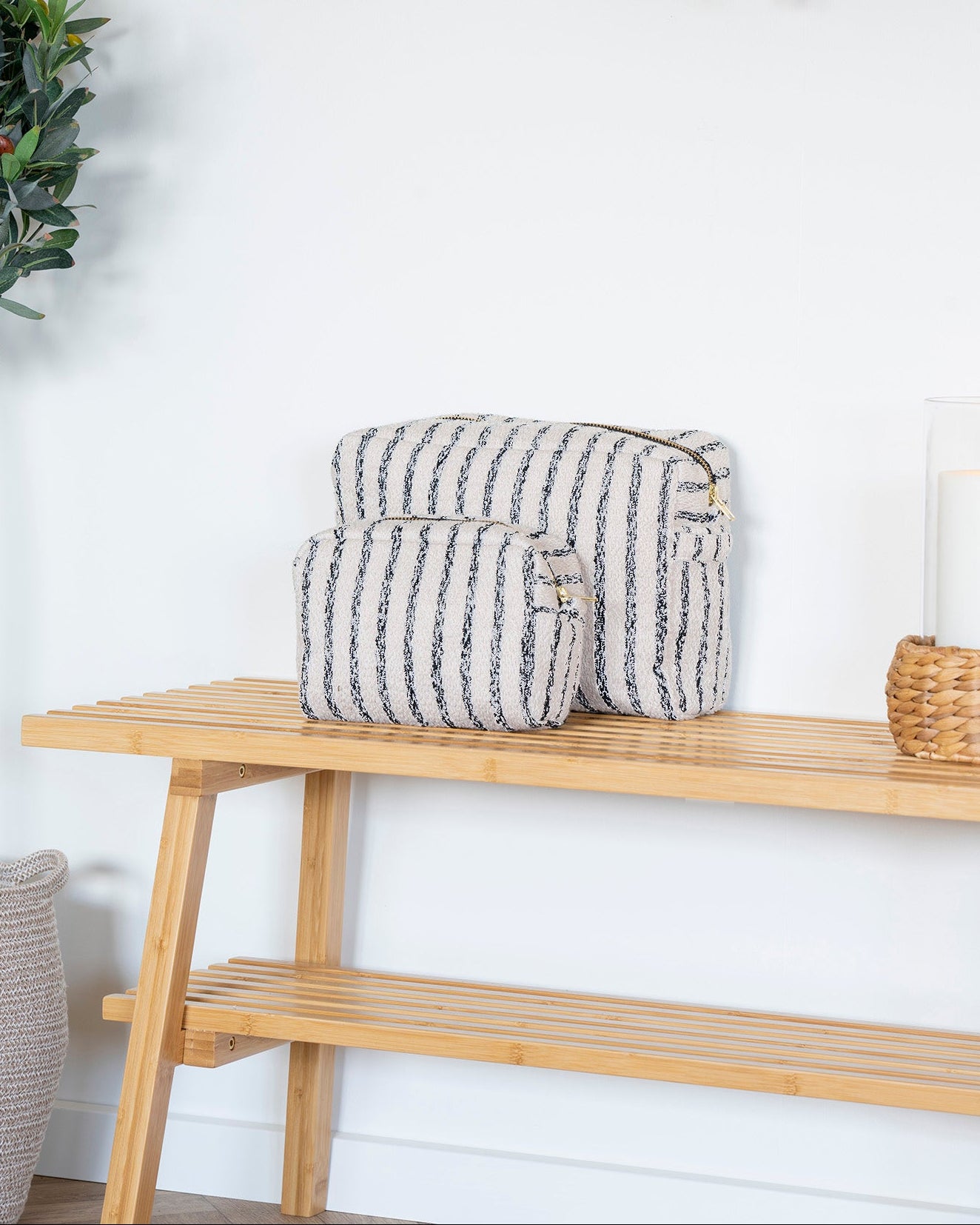 Pochette toilettasker i sæt af 2 med sandfarvet mix af strier stående på en bænk