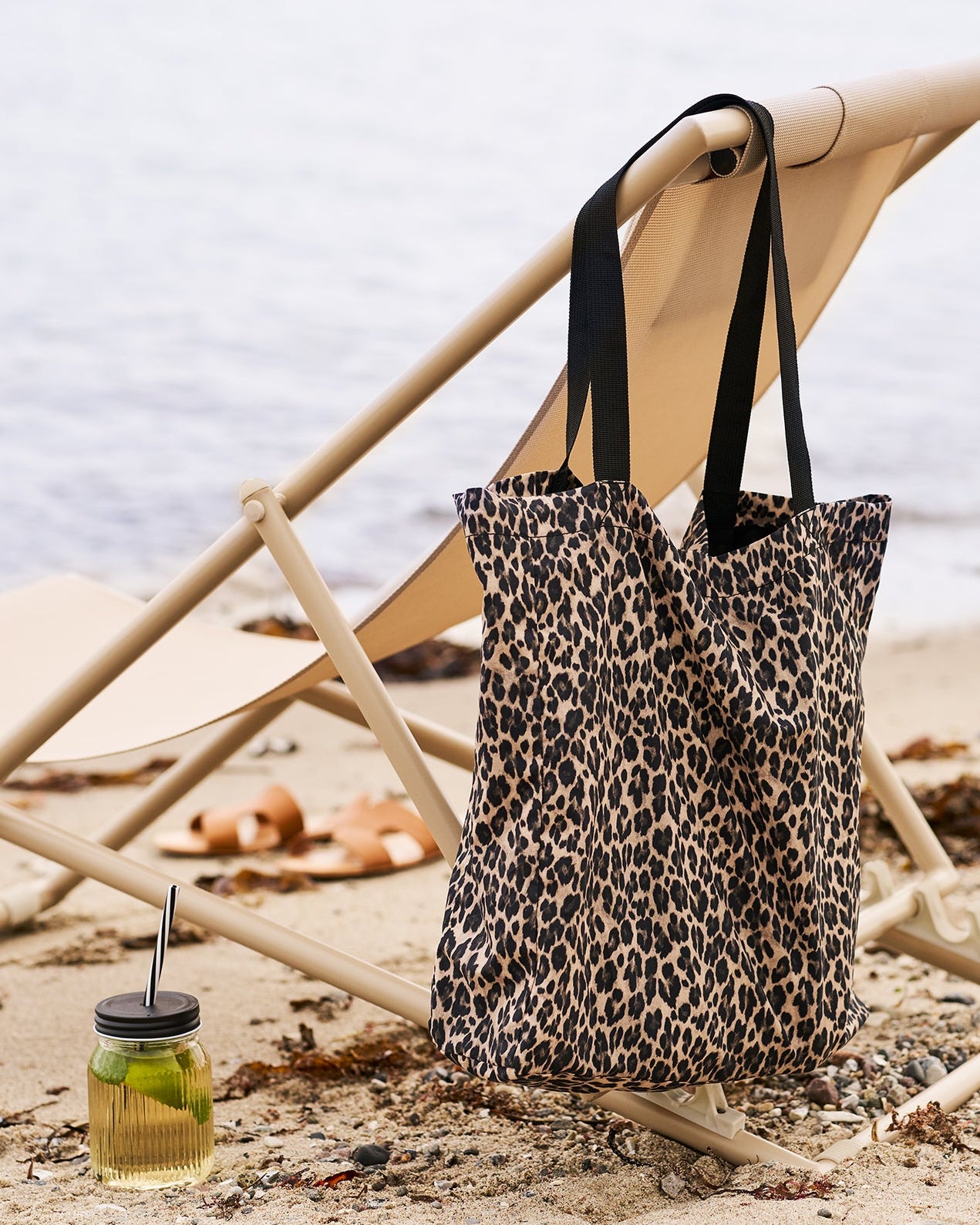 Leopardprint mulepose hængende på strandstol ved stranden
