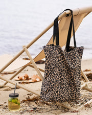 Leopardprint mulepose hængende på strandstol ved stranden
