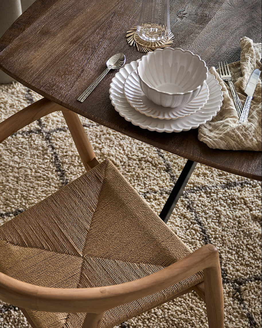 Flor frokosttallerken i hvid sammen med hvid skål og middagstallerken i samme serie. Der ses også en smukt flettet stol