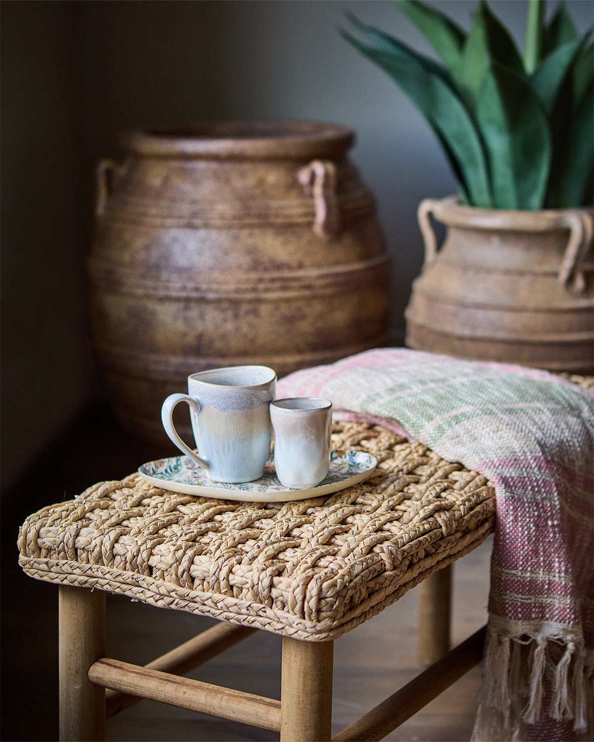 Calma kop på i beige/off white farve og reaktiv glasur på bakke og bænk med et tæppe bagved