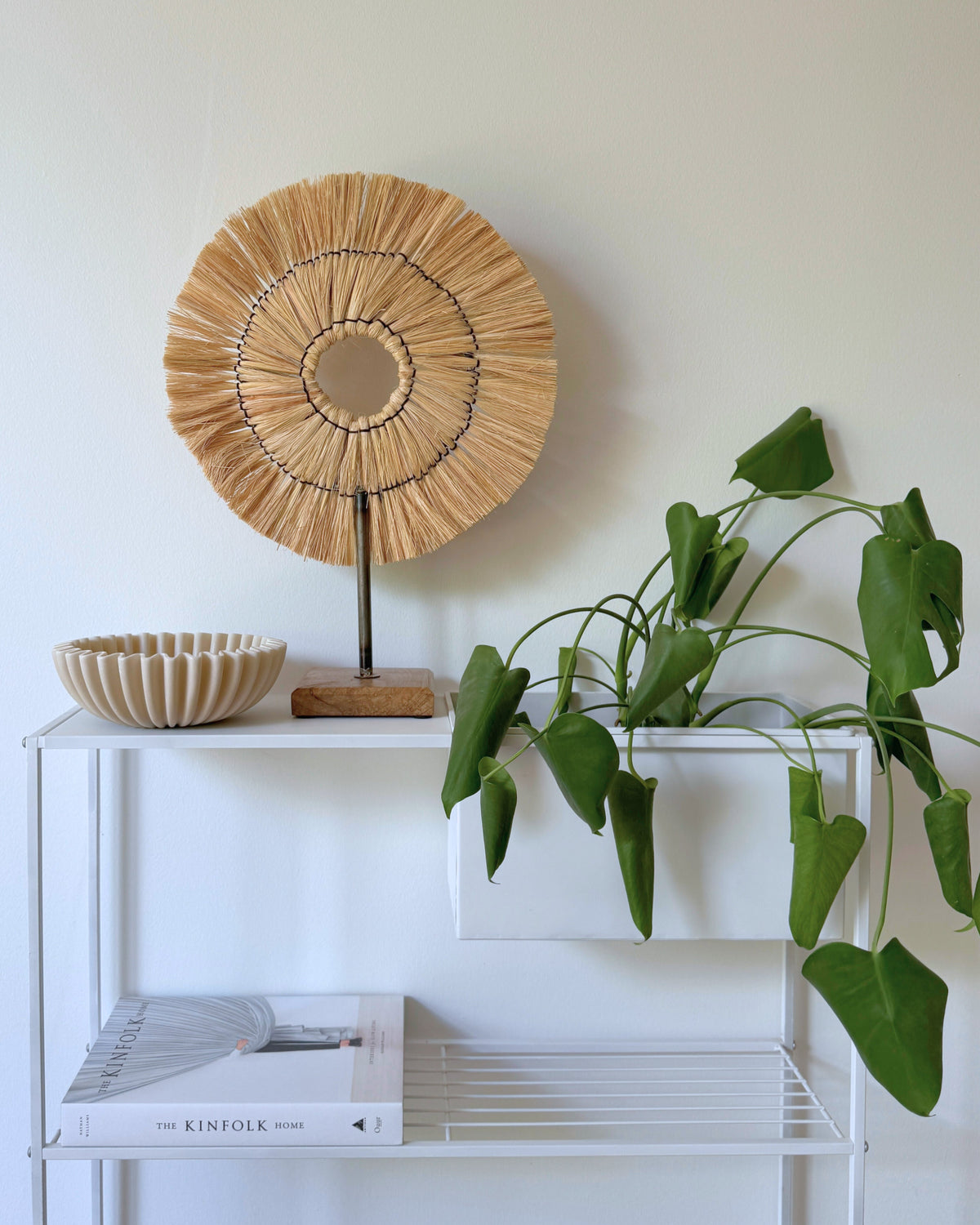 Rund dekorationsvifte på fod i naturmateriale til nordisk boligindretning på metal reol.