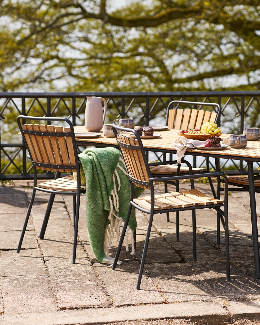 Udendørs spiseområde med havemøbler i træ og sort metal på terrasse