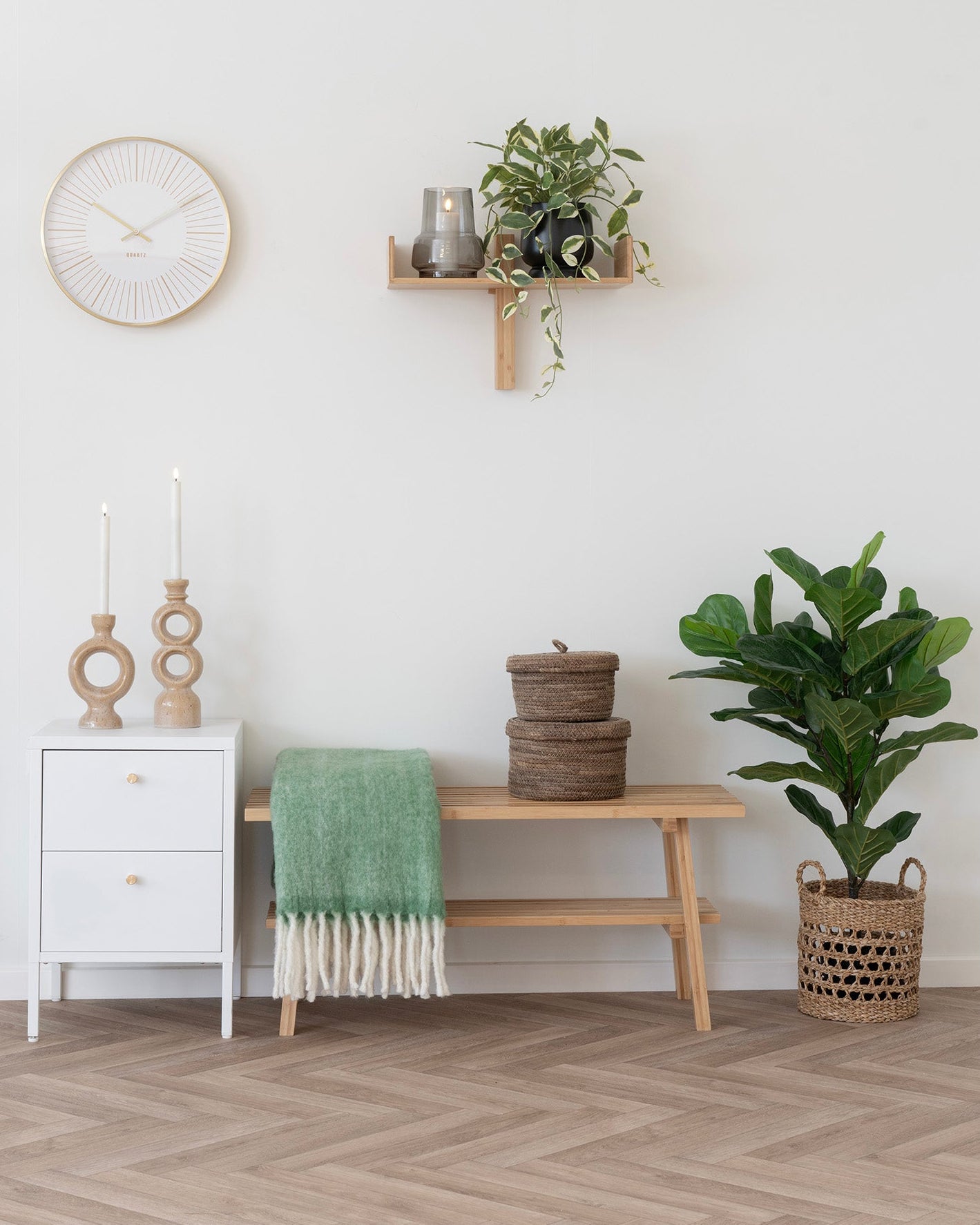 Nordisk indretning med bænk i bambus, grøn plaid og grøn plante
