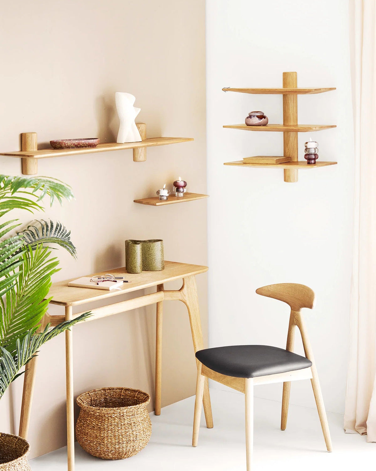 Væghylder i lyst egetræ stylet i lys indretning med skrivebord, stol og grønne planter.