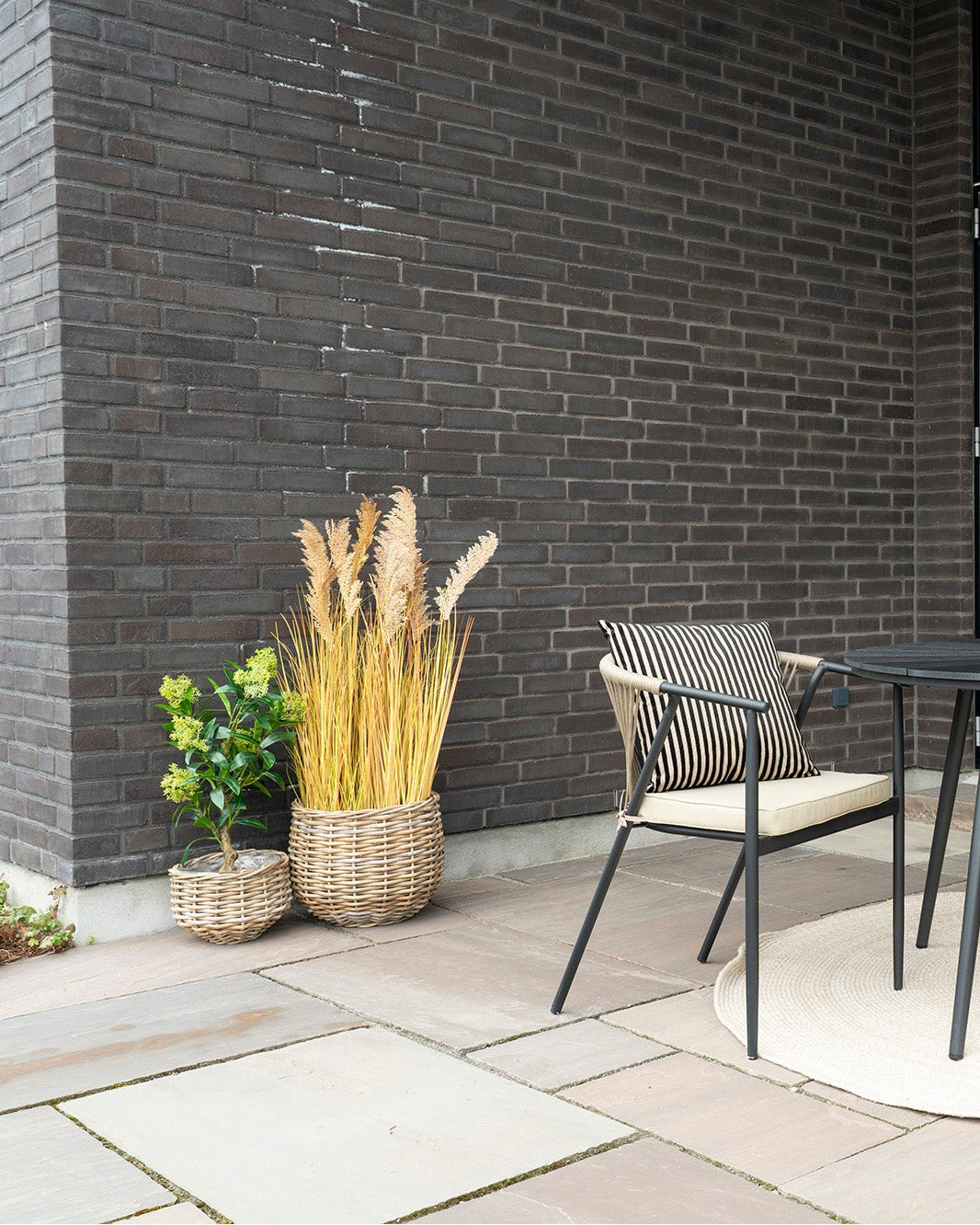 Flettede Kubu rattan kurve på terrasse med loungemøbler og naturdetaljer