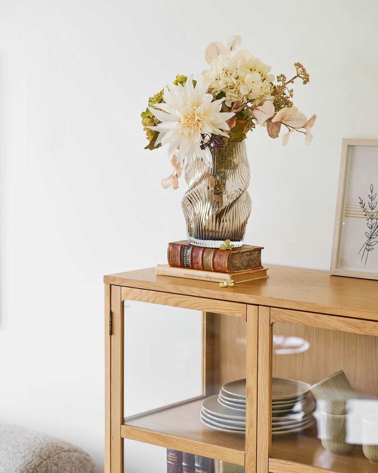 Vase i mundblæst glas på vitrineskab med tørrede blomster