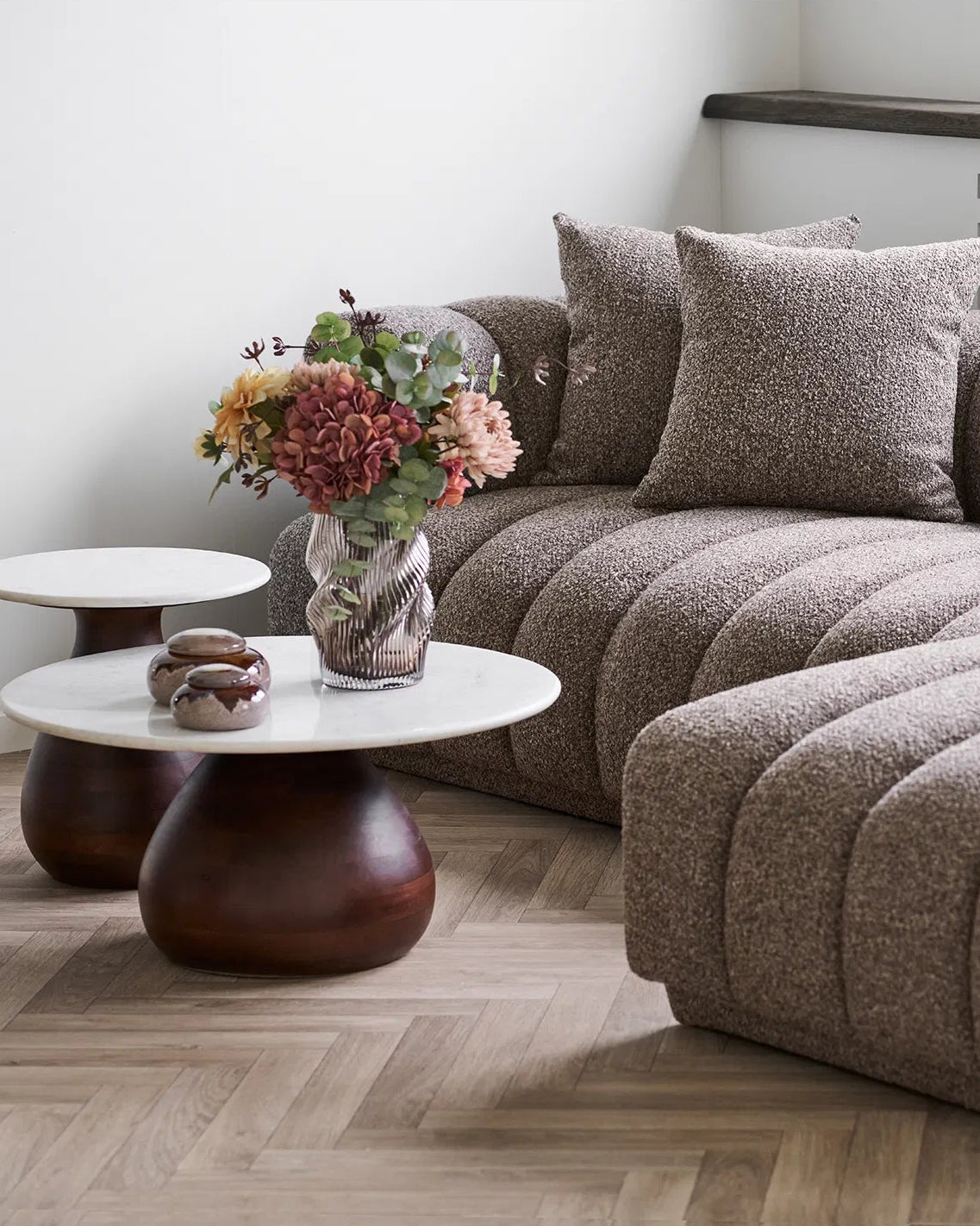 Mundblæst vase i brun med snoede organiske former på sofabord med sofa i baggrunden