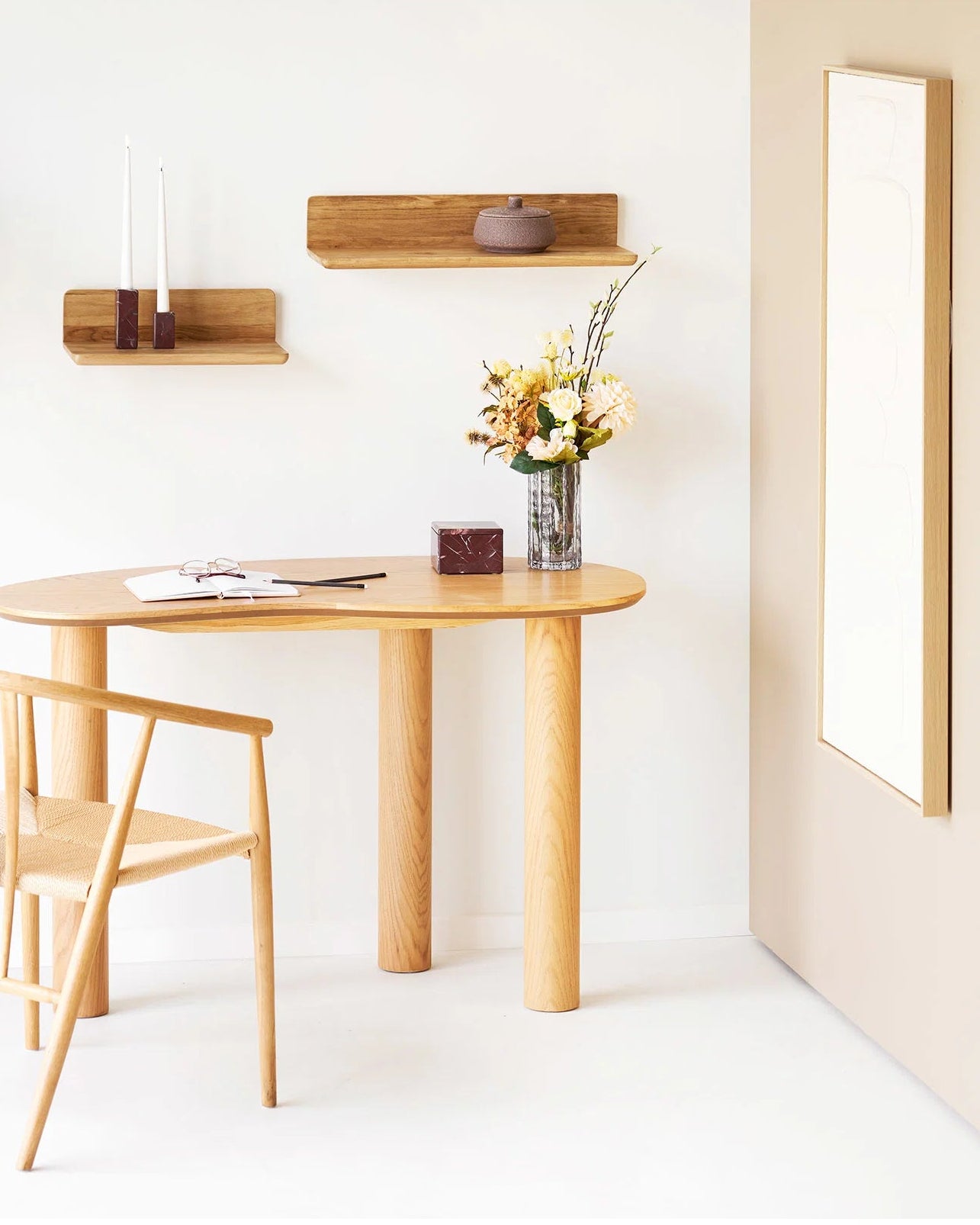 Klar glasvase med blomsterbuket på lyst træbord i minimalistisk indretning