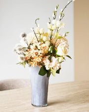 Grå glasvase med organisk form og lys blomsterbuket på spisebord