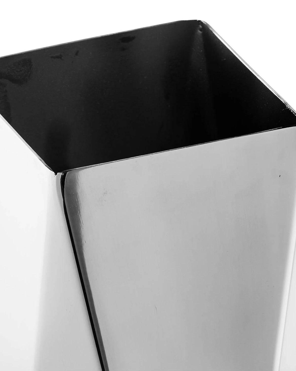 Detaljebillede af blank vase i stål med geometrisk, foldet design og reflekterende overflade.

