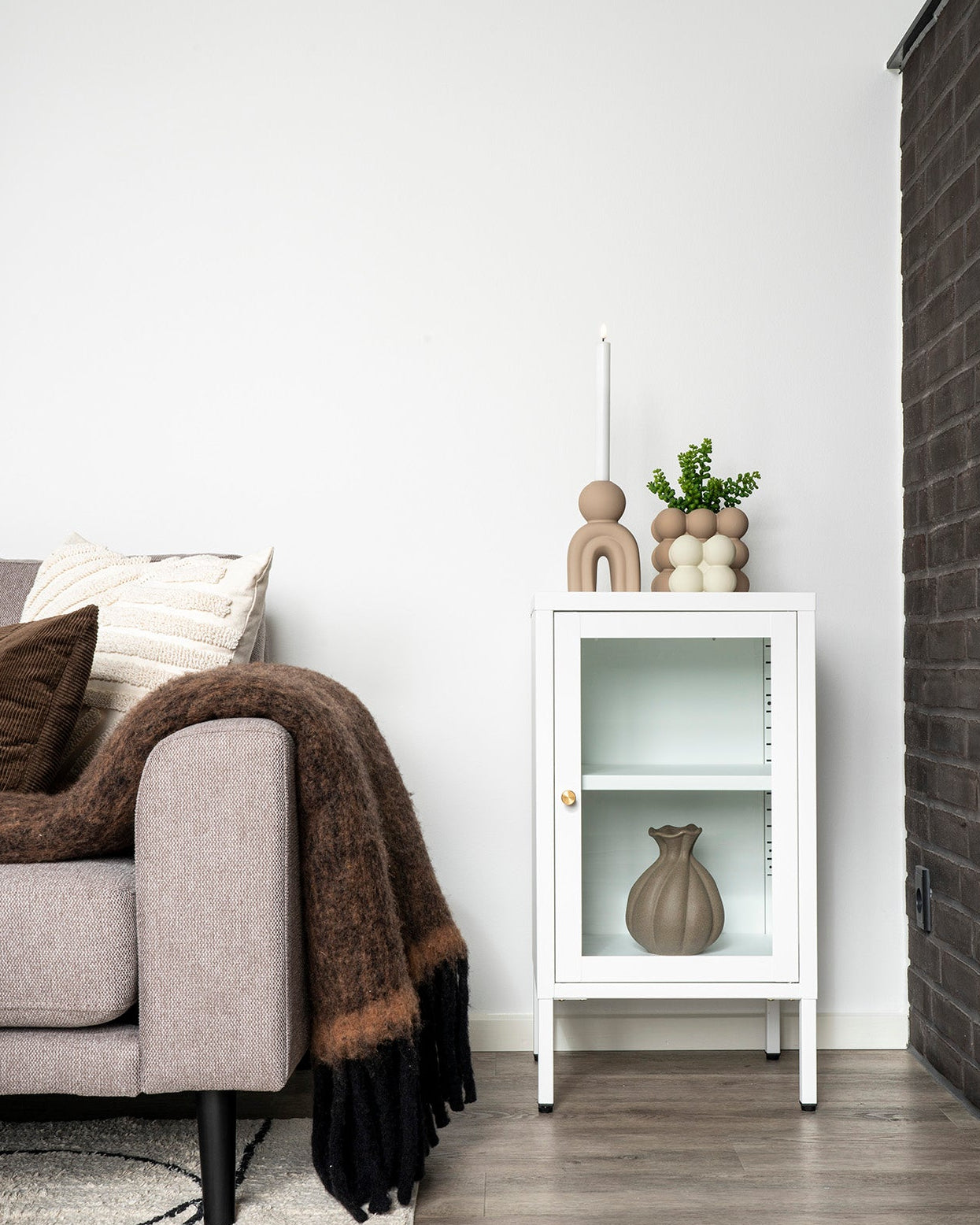 Beige lysestage med organisk design på hvidt skab i nordisk stue
