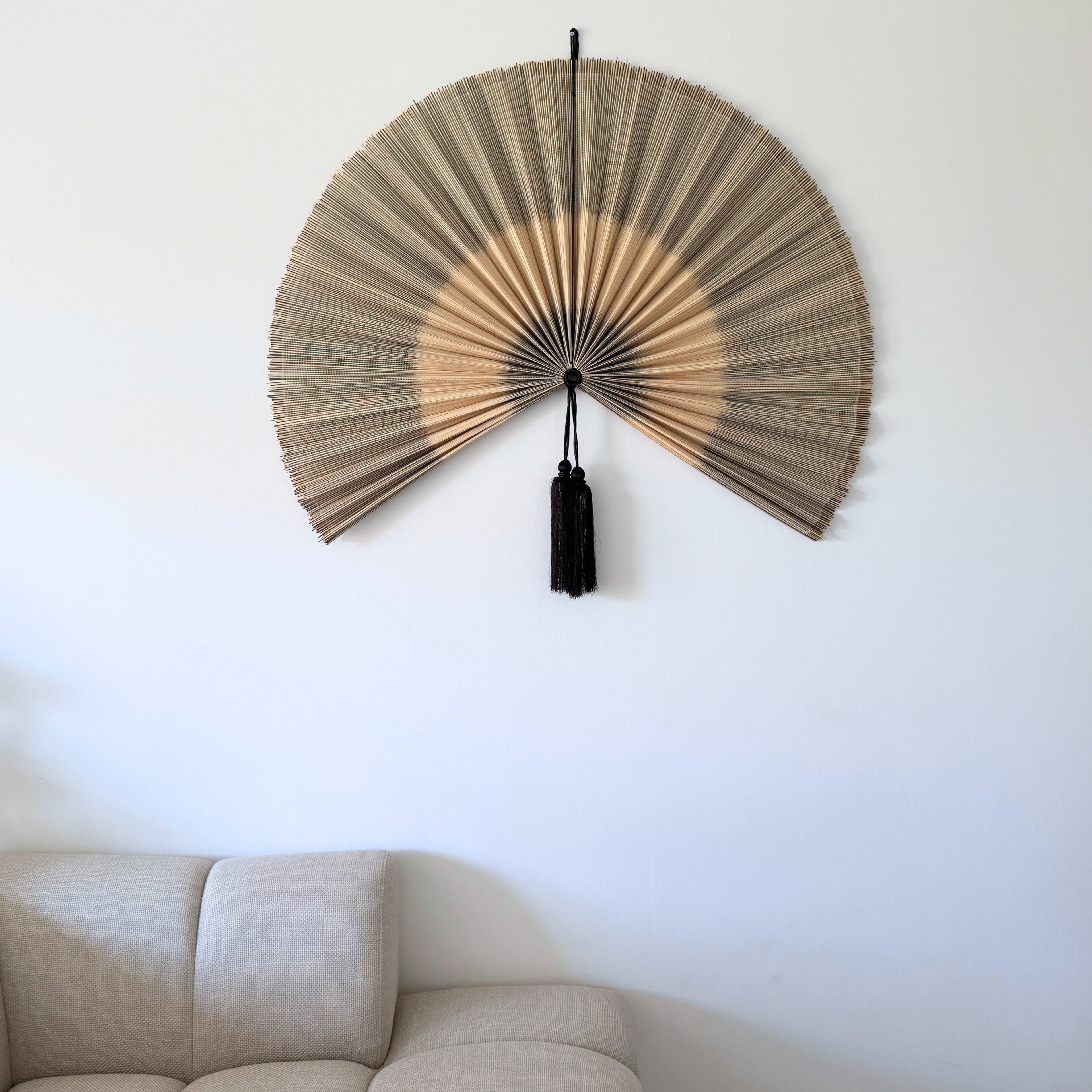 Håndlavet Saga bambusvifte i naturfarve over sofa – stilren vægdekoration i bambus