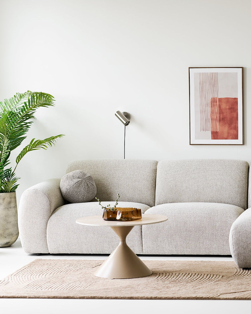 Væglampe i børstet stål over sofa i moderne skandinavisk stue
