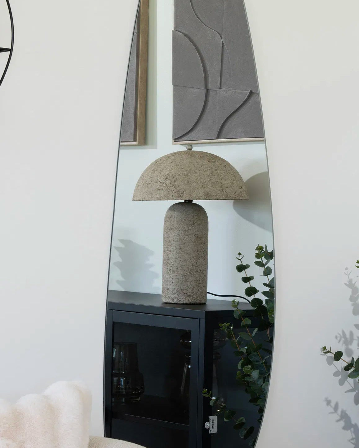 Molo bordlampe spejlet i et stort, dråbeformet vægspejl i en moderne, nordisk indretning.