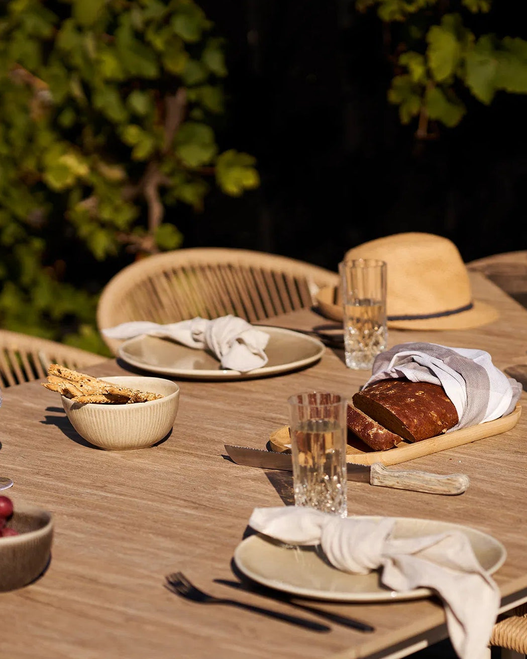 Sommerligt dækket bord på terrassen med Kyst keramikskåle brugt til servering af brød og snacks i solen.