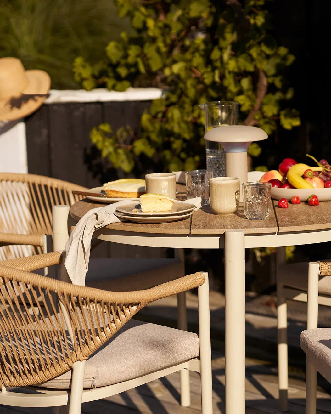 Sommerligt dækket bord på terrassen med Kyst frokosttallerkener brugt til servering af kage i solen.