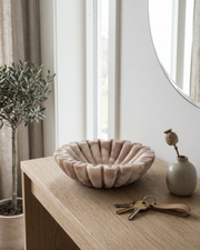 Marmorskål i hvid/rosa på bord i gang med nøgler, spejl og planter