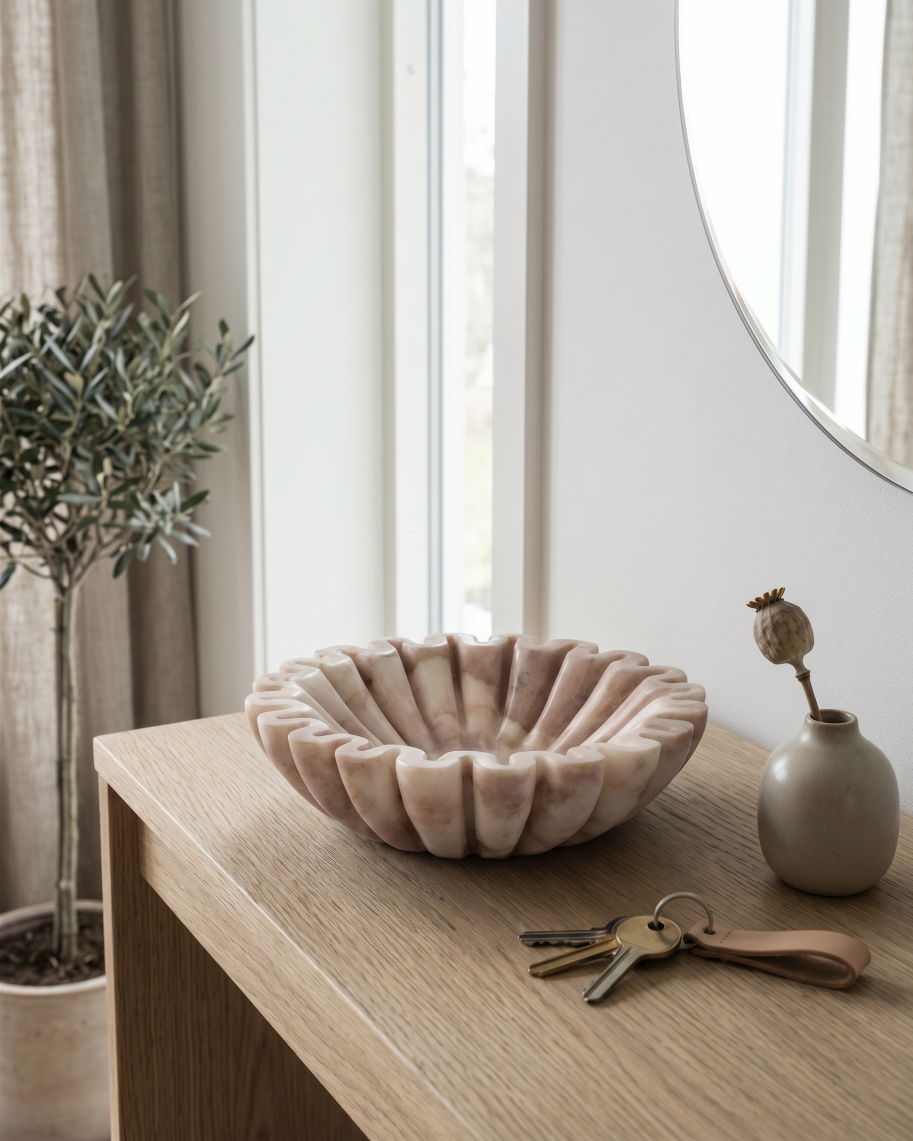 Marmorskål i hvid/rosa på bord i gang med nøgler, spejl og planter