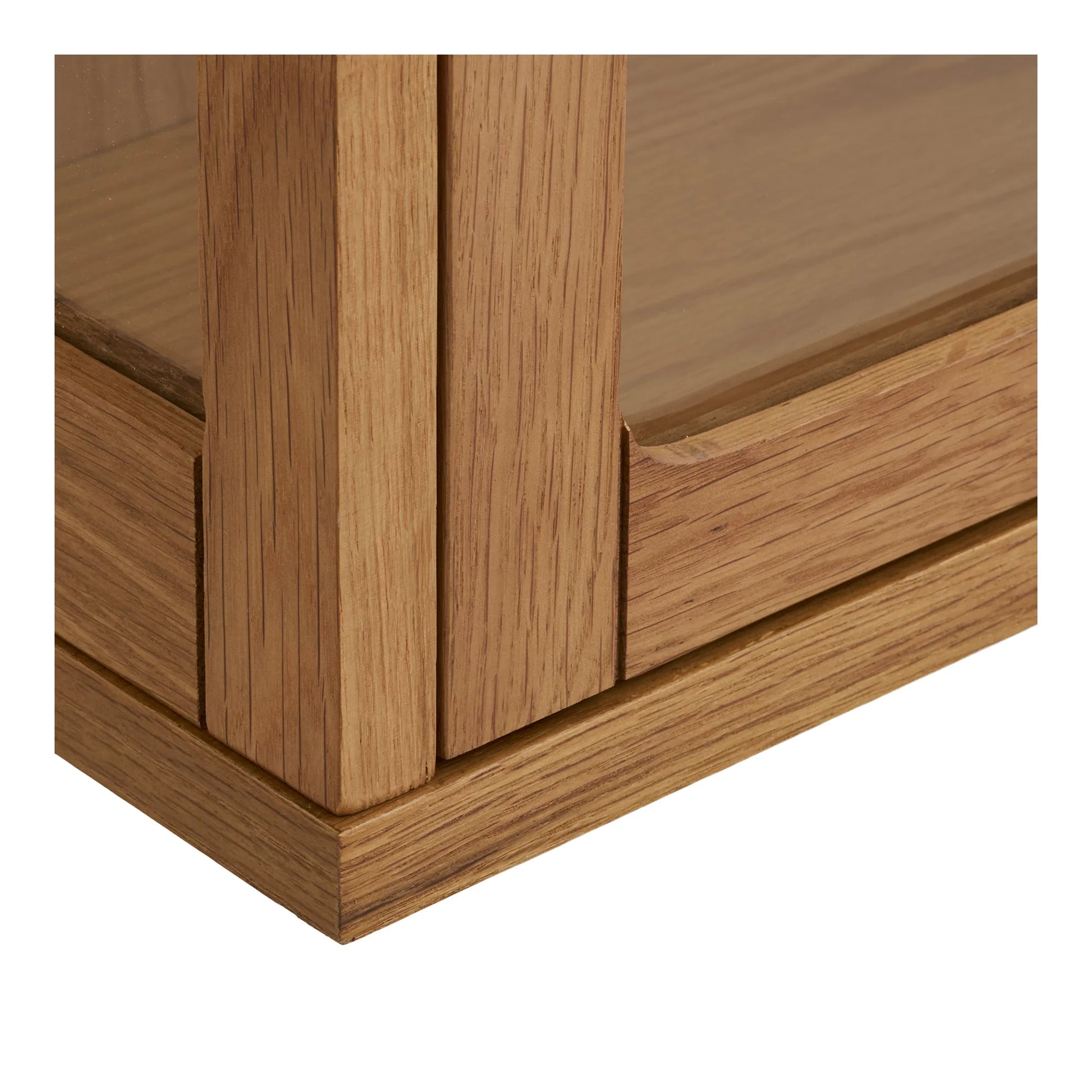 Nærbillede af Eik vitrineskabets nederste hjørne, der viser den flotte samling i egetræet og det hærdede glas.