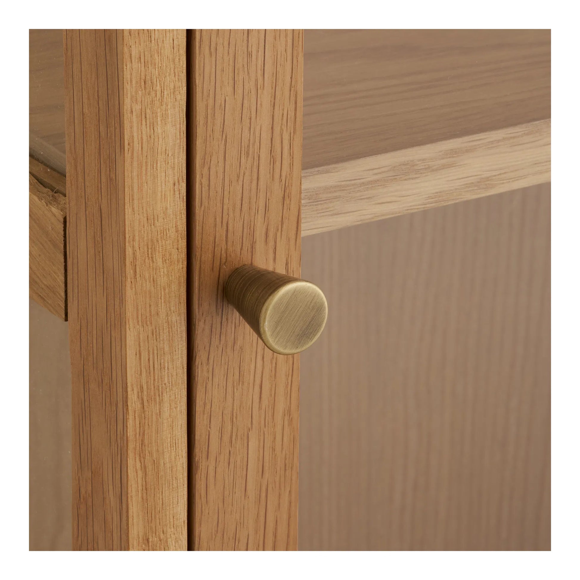 Nærbillede af den elegante messingfarvede knop på lågen af Eik vitrineskabet i egetræ.