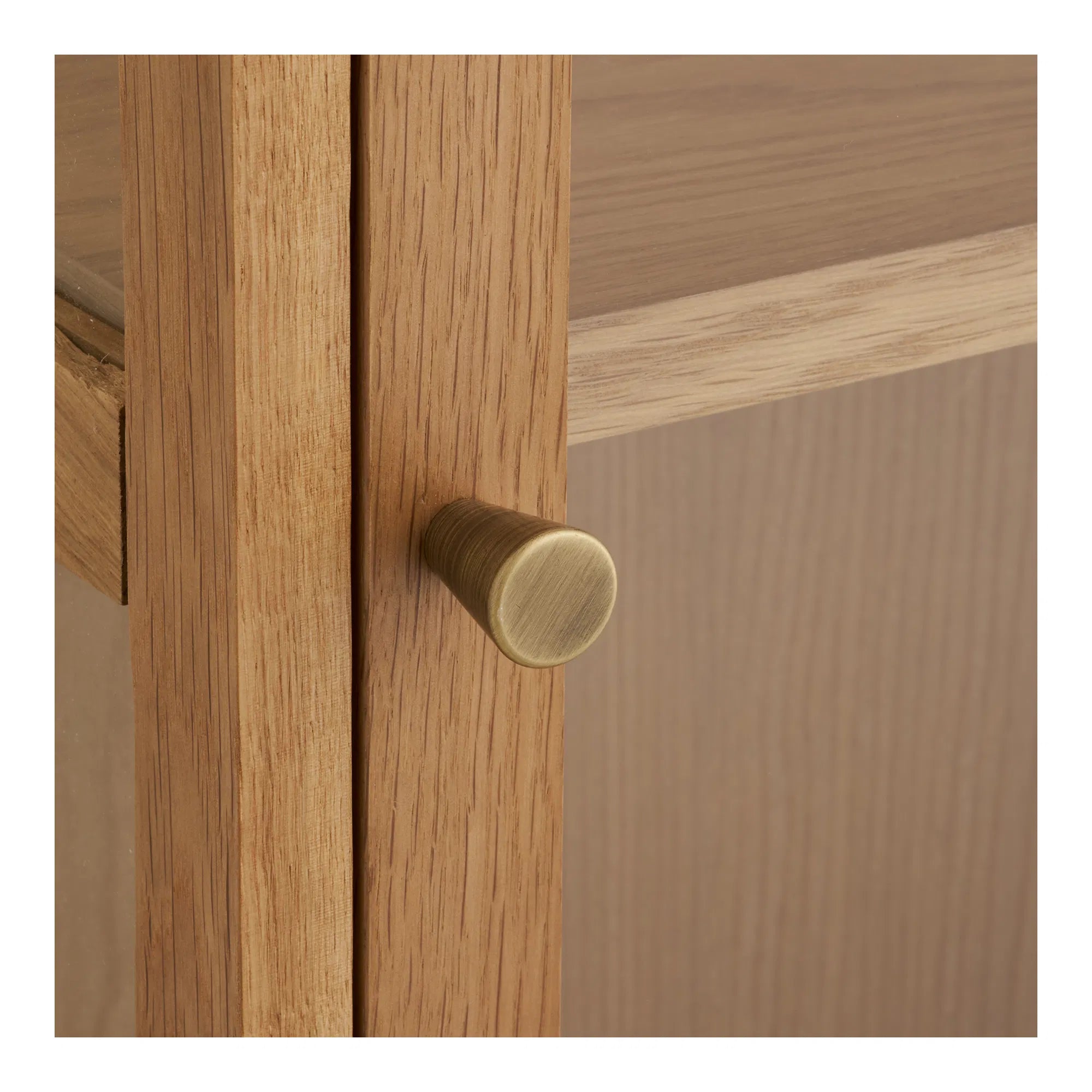 Nærbillede af den elegante messingfarvede knop på lågen af Eik vitrineskabet i egetræ.