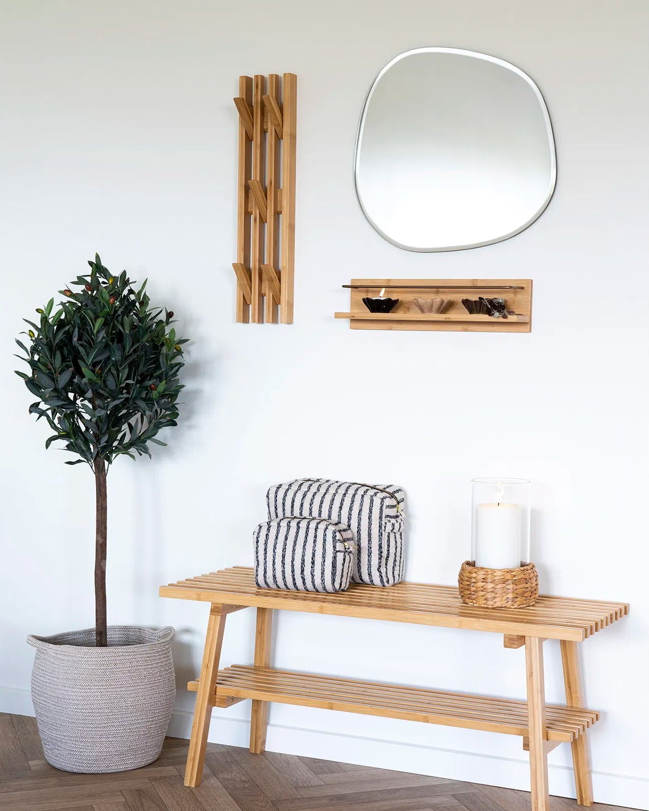 Palma bambushylde stylet i en lys entré med spejl, bambusbænk og grøn plante. Viser hylden i brug med små dekorationer.