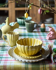 Flor Skål med frokosttallerken og middagstallerken fra samme serie i gul og off white dækket på et påskelignende bord