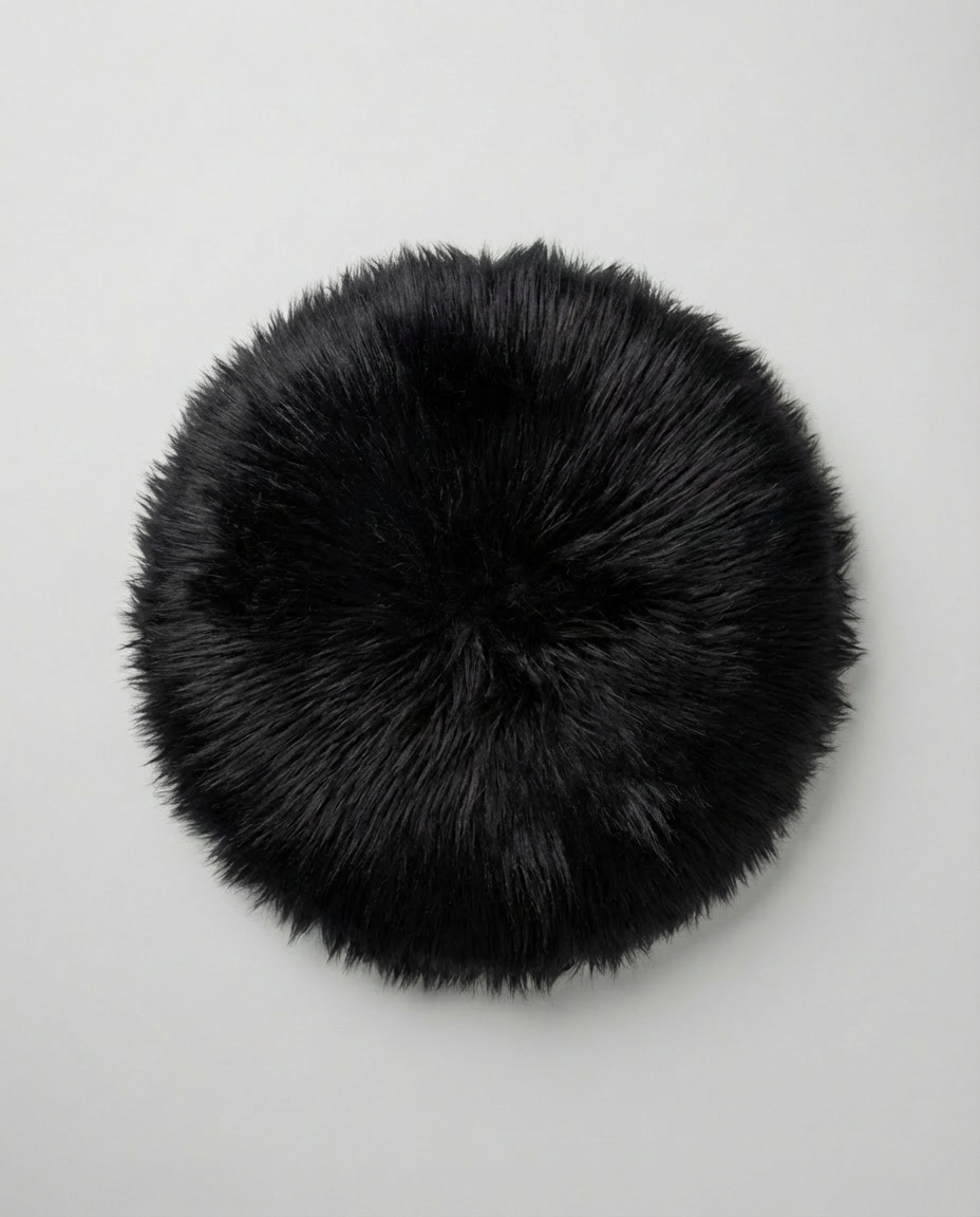 Rund sort Luna hynde med naturtro pels-look Ø35 cm på lys baggrund – Nilsson Living