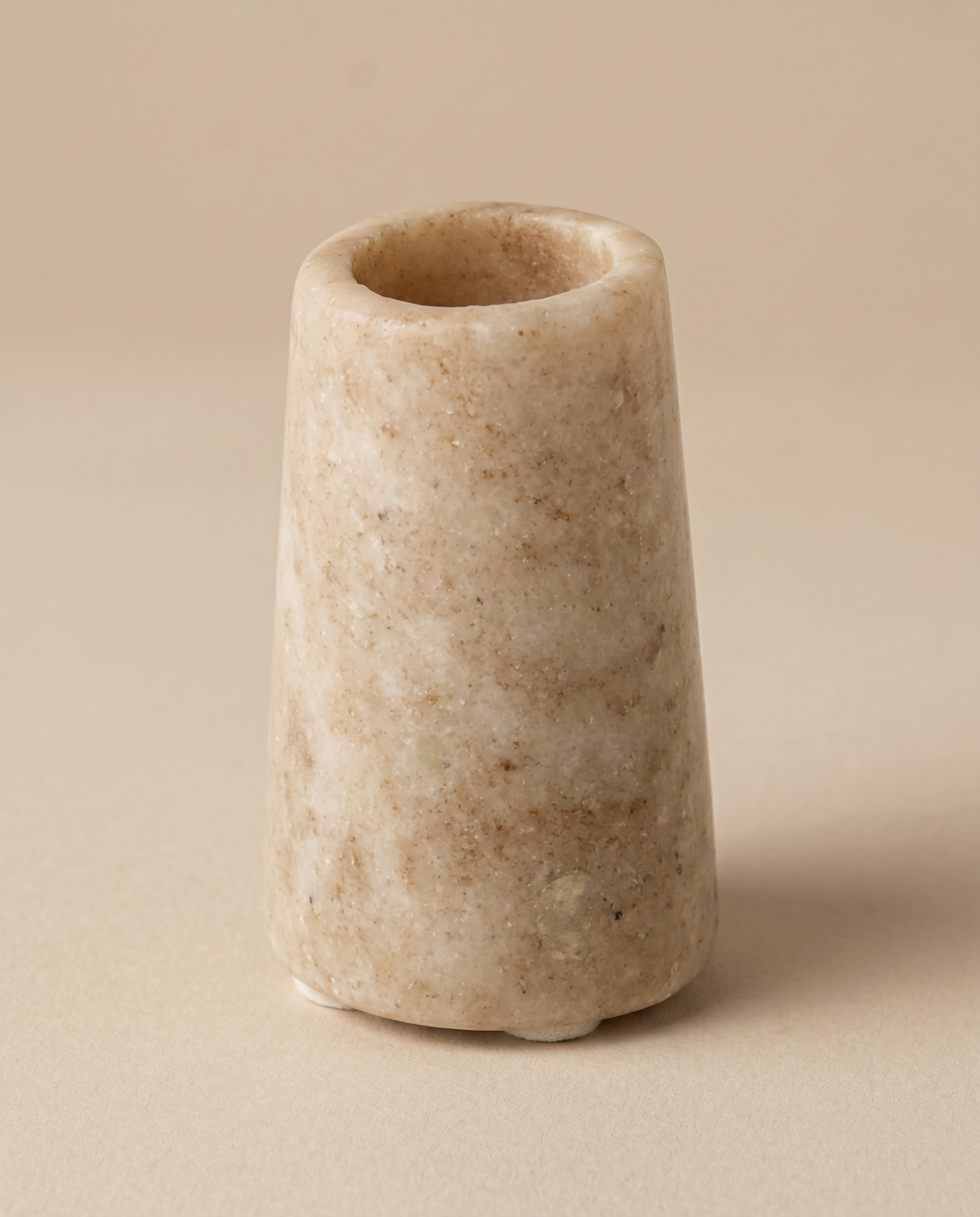 Konisk marmor lysestage i beige på beige baggrund