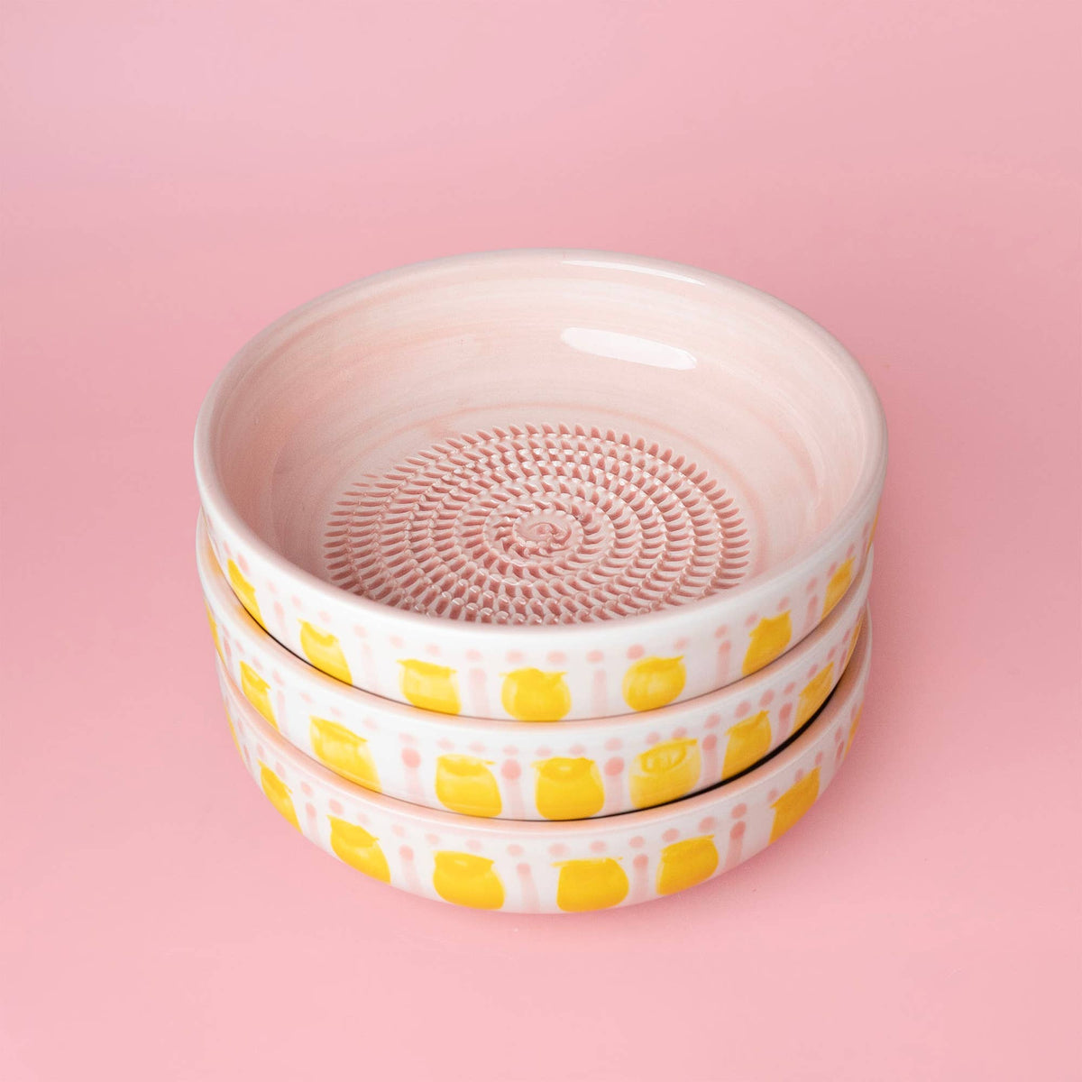 Håndlavet keramisk riveplade i pink og gul med håndmalede motiver på