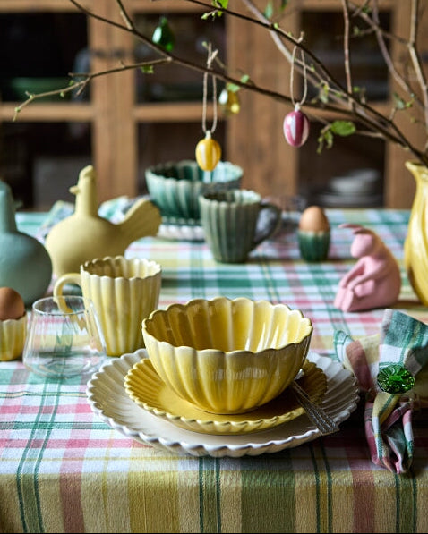 Flor tallerken i gul og off white sammen med skål i samme serie dækket på et påskebord
