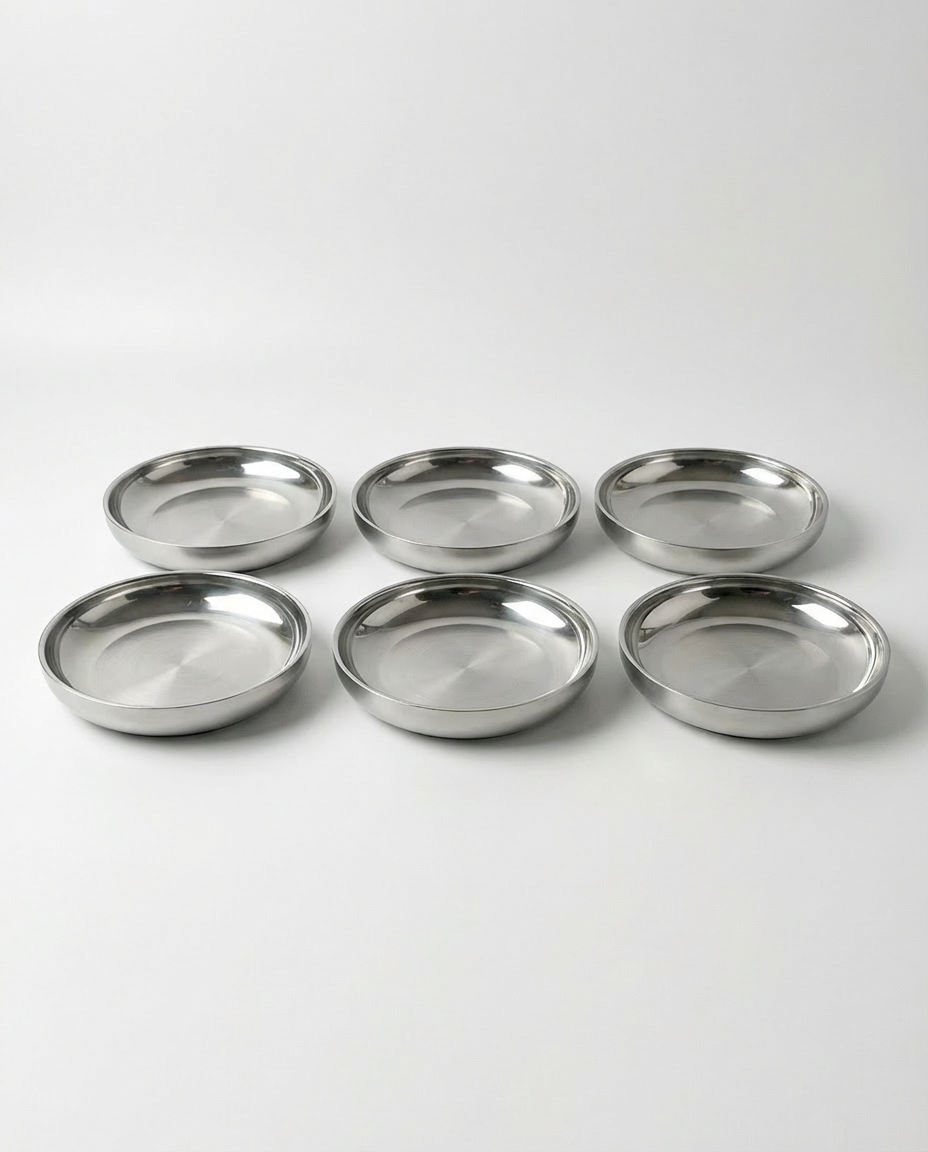 Tæt på-billede af 6 stk store ståltallerken (24 cm) på en hvid baggrund, der viser den børstede finish og den dybe kant.